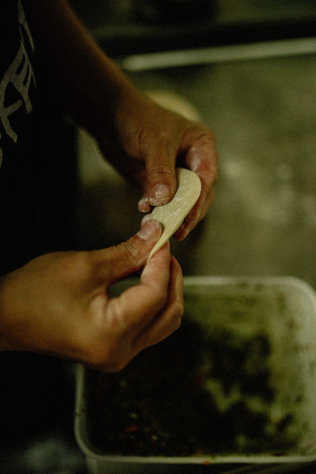 Hands folding a dumpling at BIGFAN
